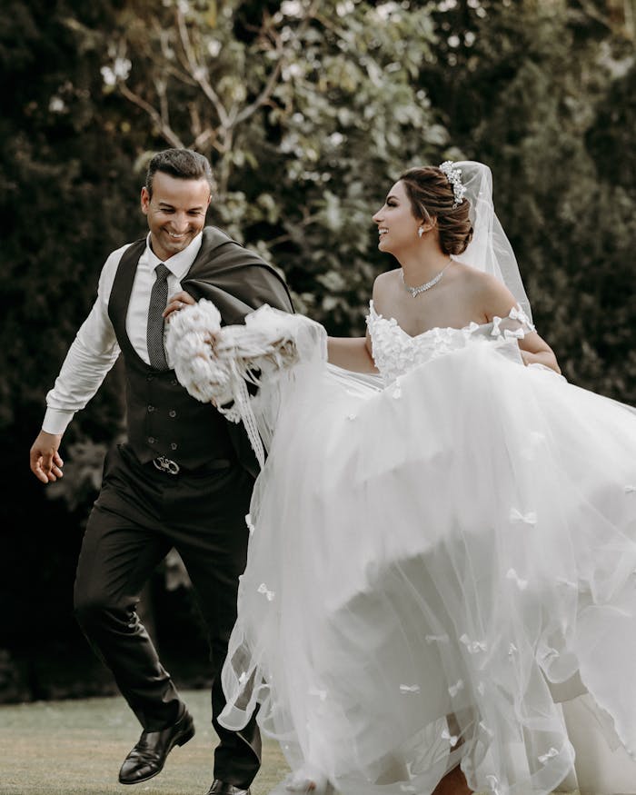 Smiling couple enjoys a dance on their wedding day, capturing romance and elegance amidst natural surroundings.