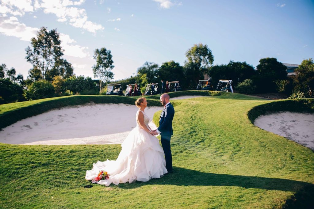 Bride and groom holding hands on a sunny day on a golf course in Colebee, NSW, Australia.